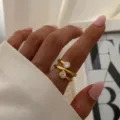 Detaillierte Makroansicht eines goldenen Wickelrings mit zwei runden klaren Steinen. - Verschlungener Wickelstil (Y01433)