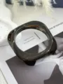 Makroansicht der Textur eines quadratischen, geometrischen Acryl-Armreifs in Marmor. - Dunkelkaffee (2519)