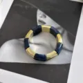 Λεπτομέρεια από μπλε ακρυλικό και χρυσό ελαστικό βραχιόλι σε φόντο ρετρό περιοδικού. - Σκούρο Μπλε
