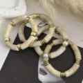Dettaglio di bracciali in acrilico crema marmorizzato con accenti in oro e perle - Set di Bracciali Curvi / Set Bianco Marmo