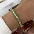 Grüner Emaille-Armreif im Boho-Stil mit elegantem Blumenmuster am Handgelenk einer Frau - Grün Emaille Rosa Blumen (885-10)