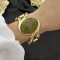 Vintage goldfarbenes breites Manschettenarmband mit einem großen grünen Edelstein - Wirbel Grün Geometrisch