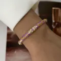 Macro detail of an elegant purple macaron enamel bangle featuring floral patterns on wrist. - Purple Enamel White Flower Gold Leaf (883-7)