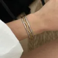 Elegantes dreiteiliges ineinandergreifendes Armbandset in Gold und Silber am Handgelenk - Wellenförmiger Ineinandergreifender Armreif (A230) / Gold/Silber