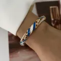 Eleganter vergoldeter Armreif mit blau-weißen Emaille-Spiralen und funkelnden Kristallen. - Gold Basis Blau Weiß Streifen Strass Stil (882-5)