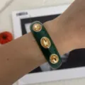 Detaillierte Nahaufnahme eines grünen Emaille-Armreifs mit bernsteinfarbenen Kristallen - Geometrischer Strass-Stil (2557) / Grün