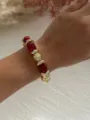 Primo piano dettagliato di un braccialetto vintage con perle rosse e dorate sul polso - Rosso Vino e Oro