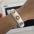 Detaillierte Nahaufnahme eines weißen Emaille-Armreifs mit drei goldgelben Kristallen. - Geometrischer Strass-Stil (2557) / Weißgold