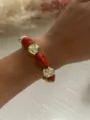 Primo piano di un bracciale vintage con perle rosse marmorizzate irregolari - Arancione e Oro