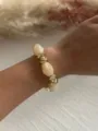 Nahaufnahme eines Retro-Acryl-Perlenarmbands mit goldenen geometrischen CCB-Perlen - Milchkaffee & Gold