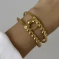 Bracciale rigido aperto oro largo con esclusivo design a sfere testurizzate per donna - Stile Incrociato a Doppio Anello