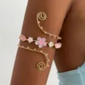 Dettaglio macro di un bracciale a spirale dorato con fiori di ciliegio e perline - Bracciale da Braccio in Cristallo Floreale Multicolore (1)