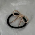 Dettaglio di un fiocco minimalista in corda dorata su un elastico per capelli nero. - Elastico per Capelli con Fiocco Intrecciato (2025397) / Oro