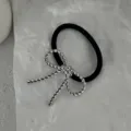 Primo piano del dettaglio del fiocco in corda d'argento su elastico per capelli nero - Elastico per Capelli con Fiocco Intrecciato (2025397) / Argento