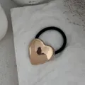 Detailaufnahme eines glänzenden goldenen Herz-Haargummis aus Legierung auf weißem Grund. - Herzmotiv Haargummi (2025397) / Gold