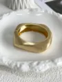 Macro view showing the brushed metal texture of a matte gold geometric wave bangle - Pebble Shape Style (Matte Gold 529) / Matte Gold 529