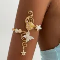 Vista dettagliata del bracciale dorato con farfalla e conchiglia indossato sul braccio. - Bracciale da Braccio Stella Marina Farfalla (5)