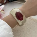 Vintage marbled resin wide bangle bracelet with red oval stone inlay shown on a model's wrist - Marbled Dark Red