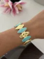 Bracciale a fascia dorato con maglie in smalto turchese marmorizzato su un polso - Ovale / Blu/Oro
