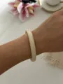 Eleganter minimalistischer creme-weißer runder Harzarmreif im Retro-Stil am Handgelenk - Dünner Runder Stil / Marmor