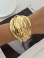 Elegante bracciale rigido dorato largo con un'esclusiva finitura in metallo ondulato - Stile Oro Ondulato (814 Gold)