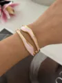 Elegante vergulde open armband met roze gemarmerd emaille inleg op de model pols. - Onregelmatige Ring Roze