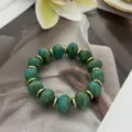 Elegantes grünes Perlenarmband aus Kunststein mit goldenen Zwischenstücken im Bild - Unregelmäßiger Perlenstil (823) / 13 Stück (10mm) / Seegrasgrün