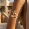 Primo piano del bracciale dorato con stella marina e perla indossato in un resort - Stile Stella Marina Perla 05