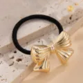Dettaglio macro di un elegante elastico per capelli con fiocco dorato su pietra testurizzata - Elastico per Capelli Fiocco a Righe (820571) / Oro