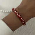 Close-up detail of a vintage red enamel floral bracelet being worn on a woman's wrist. - 6CM Diameter / Red Floral (BR26Y0269-2)