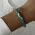 Close-up of a blue enamel bangle with golden floral patterns in retro Chinese style - 6CM Diameter / Sky Blue Court Style (2#BR26Y0270-1)