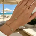 Gold chain hand harness with turquoise flower charms shown on hand at a sunny beach. - Green Artificial Pearl Hand Chain