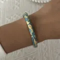 Close-up of a vintage light blue enamel bangle with gold floral patterns on a wrist - Light Blue Gold Relief Floral Style (25)
