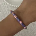 Detailed view of a vintage purple enamel bangle featuring delicate pink floral patterns on wrist - Purple Pink Floral Gold Trim Style (43)