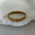 Elegant gold-toned square link stretch bracelet displayed on a white ceramic dish. - Stretch Bracelet (Geometric Cut) / Gold