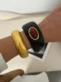 Chunky bohemian resin bangles set worn on wrist for an elegant ethnic jewelry style. - Black and Shiny Gold Combination