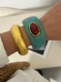 Gros plan d'un bracelet en résine turquoise de style bohème et d'un jonc doré. - Turquoise et Or Brillant Combinaison