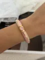 Elegant enamel bamboo-style bangle in pink and cream with gold-tone finish on a model's wrist - Bamboo Open Bangle / Pink and White Gold
