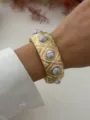 Exquisite vintage gold alloy cuff bracelet with marbled white stones worn on a wrist - Wide White Turquoise Style (A656)