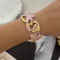 Exquisiter Armreif mit rosa Emaille-Seestern und Seepferdchen-Motiv in Gold-Optik am Handgelenk - Seestern Rosa-Stil