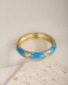 Eleganter breiter goldener Armreif mit blauen Emaille-Akzenten auf strukturiertem Stein-Hintergrund. - Blau Gold Geometrisches Muster (4583)