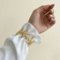 Elegante bracciale rigido a forma di stella marina dorata su una manica bianca - Stile Stella Marina (0116)