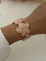 Vergoldeter Emaille-Blumen-Armreif mit rosa Blütenblättern am Handgelenk eines Models - Rosa Glasur Blume Offener Armreif