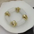 Minimalistische armband met grove gouden gehamerde kralen en witte acrylhars kralen - IJskristal Wit Stijl
