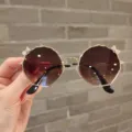 Macro view of fashionable children's metal sunglasses featuring sparkling crystal bow accents - Gold Frame Tea Lens