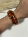 Amber resin segmented elastic bracelet with gold-toned spacers on wrist - Amber Brown