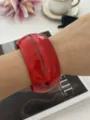 Elegante bracciale rigido largo in resina rossa con venature effetto agata su un polso - Rosso