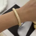 Elegant vintage cream bangle with gold floral engraving shown on a model's wrist - Vintage Floral Embossed Style / Creamy White/Gold