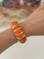 Bracciale elastico in resina marmorizzata arancione acceso con accenti metallici dorati al polso - Arancione Tramonto