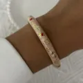 Vintage pink enamel bangle with delicate golden floral patterns on model's wrist - 6CM Diameter / Light Pink Enamel Floral (BR26Y0277-3)